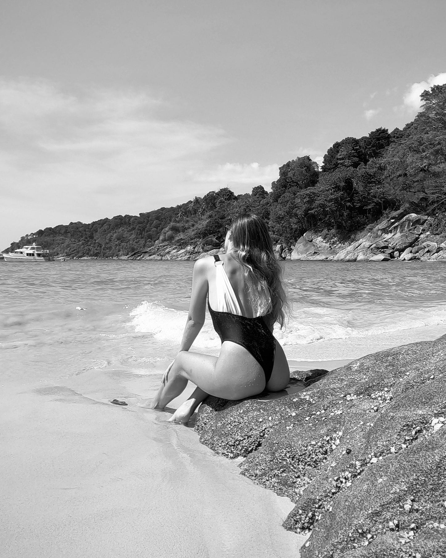 Selena one-piece by XY Swimwear. Black swimsuit. One-piece swim featuring scoop neckline and high-leg cut. Open back with contrasting white straps and metal O-rings. Black swim. Black swimsuit. High leg swimsuit. High cut swimsuit. Sexy swimsuit. Singapore swimwear brand. Sustainable swimwear. Recycled fashion. Recycled Swimwear. Repreve fabric swimwear. Singapore based fashion brand. High fashion swimwear. Vacation wear. Holiday wear. Medium coverage swimsuit.
